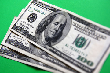 three 100 dollars banknote on the green background