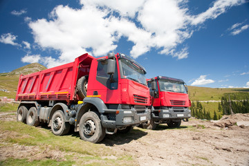 Two large red dump trucks