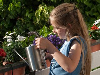 Kind gießt Balkonblumen