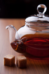 glass teapot with black tea and sugar cubes