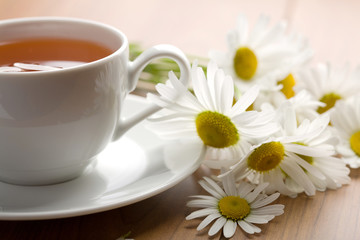 Fototapeta na wymiar white cup of herbal tea and camomile flowers