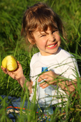 girl with plastic bottle eats green apple in grass