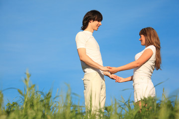 Fototapeta na wymiar girl and guy stand on grass having joined hands