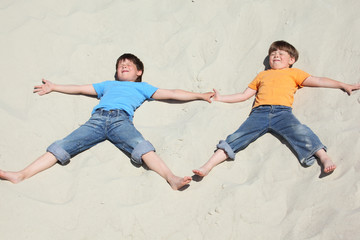 Fototapeta na wymiar Two children lying nearby on sand