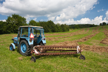 Old tractor with trailer collecting  grass