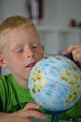 Portrait d'un petit garçon assis faisant tourner un petit globe