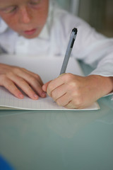 Petit garçon écrivant sur un cahier avec un stylo noir