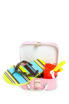 small suitcase with sand toys and green striped slippers