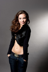 seductive young girl with hands in pockets separated over gray