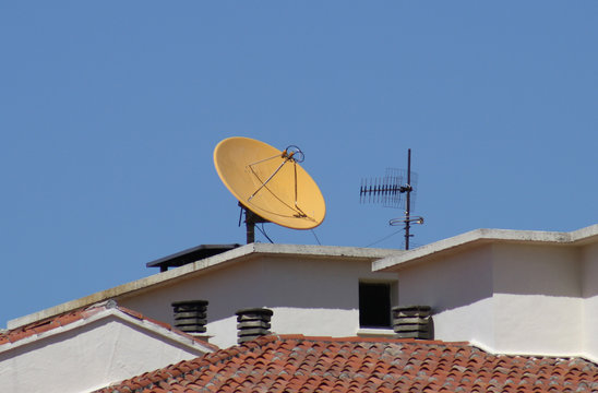 Antena parabolica amarilla en el tejado.