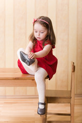 Little girl sitting on table and put on one's shoes