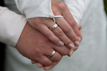 Hände von einem Hochzeitspaar mit Ring und Kleid