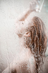 showering woman shot from behind glass
