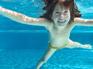 kleines Mädchen lacht fröhlich beim Tauchen im Pool