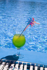 Glasses stand with cocktail on edge of pool