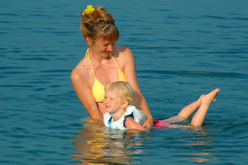The woman learns the small child to float