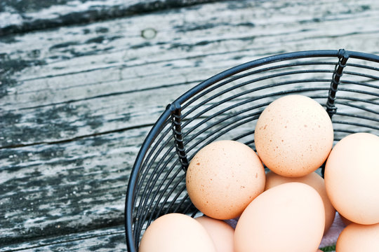 Basket of freshly laid free range eggs on rustic background.
