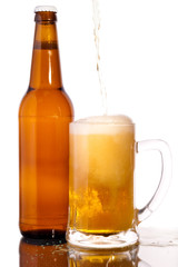 Glass of beer in the front with foam with bottle of beer