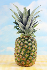 One whole pineapple against a cloudy blue sky.