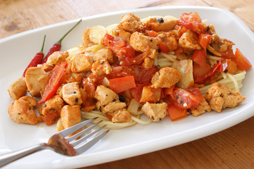 Spaghetti with tomato and chicken meat on a plate
