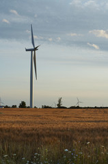 windmills stand against a blue cloudy sky.