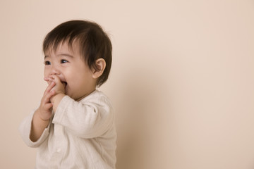 口に手を入れて喜んでいる赤ちゃん