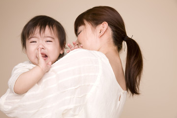 母親に抱っこされながら泣いている赤ちゃん