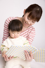 母親に本を読んでもらっている赤ちゃん