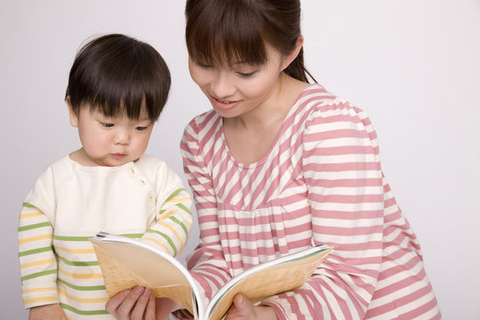 母親に本を読んでもらっている赤ちゃん