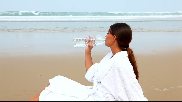 Femme buvant de l'eau min&eacute;rale face &agrave; l'oc&eacute;an
