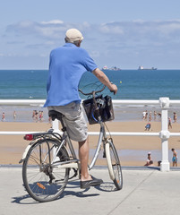 Anciano en bicicleta frente a la playa