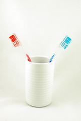 red and blue tooth brushes in white cup