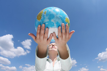 woman holding a globe under blue sky