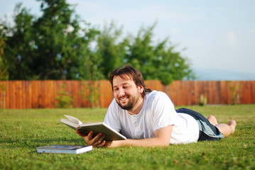 Young man is laying on green ground and learning