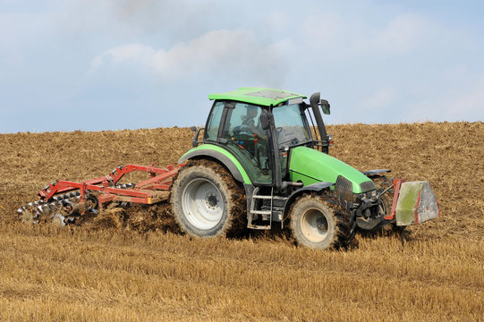 g&uuml;ner Traktor beim Pfl&uuml;gen