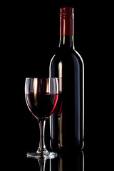 Glass of wine and bottle of wine on black