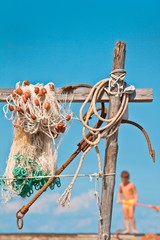 Fishnet with anchor in background with a little boy