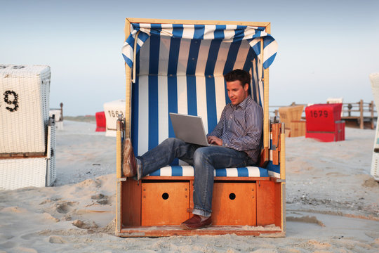 Geschäftsmann bei der Arbeit am Strand mit Laptop