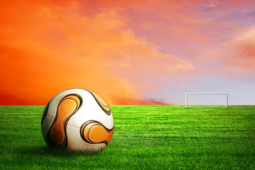 Soccer ball on green grass and sunrise sky background
