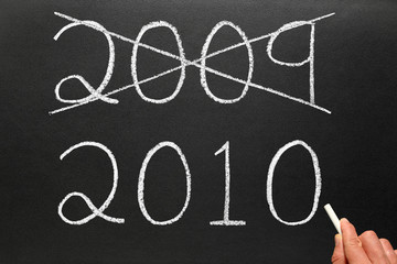Crossing out the old year 2009 and writing 2010 on a blackboard.