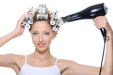 woman with hair-curles and hairdryer doing hairstyle