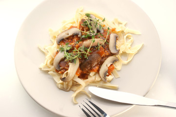 Pasta with mushroom and organic herbs on a pink plate