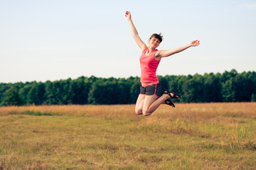 Happy woman jumping in yellow field