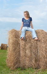 Naklejka na ściany i meble Beautiful girl sits on hay