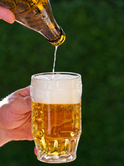 Bier aus einer Bierflasche wird in Bierglas eingeschenkt