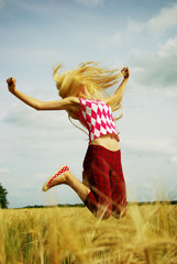 Teenage girl jumping in the air with sky as background.