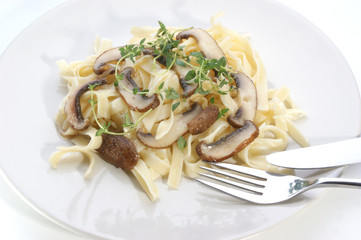 Pasta with mushroom and herbs on a white plate