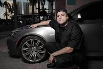 Fototapeta na wymiar Young man posing next to a luxury car on the street