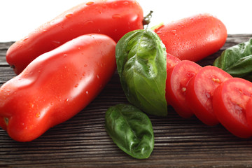 Flaschentomaten mit Basilikum auf verwittertem Holzbrett