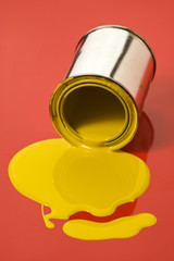 gelbe farbdose läuft aus auf rotem untergrund